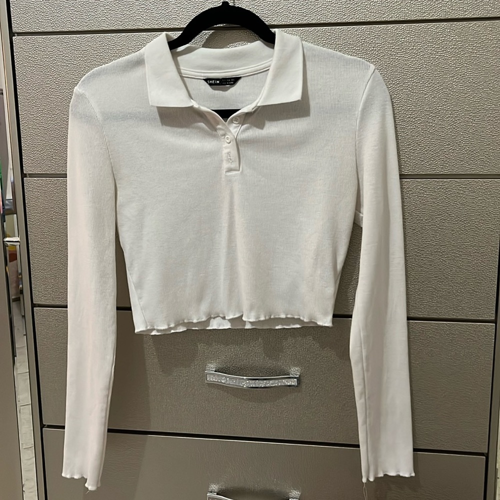 White polo shirt from shein with ruffle ends on the sleeves and bottom of shirt.